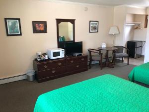 a hotel room with a bed and a desk with a tv at Mansion House Motel in Buffalo