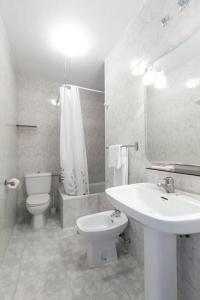 bagno bianco con lavandino e servizi igienici di Pensión Dorotea a Lavacolla