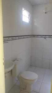 a white bathroom with a toilet and a sink at Pousada Potiguara Irapuan in Iranduba