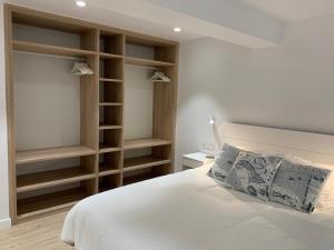 1 dormitorio con cama blanca y estanterías de madera en Aldamar apartamentua PARKING INCLUIDO en Getaria