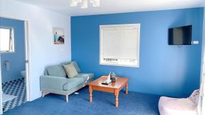 ロトルアにあるPanoramic View Apartment Without a Kitchenの青いリビングルーム(ソファ、テーブル付)
