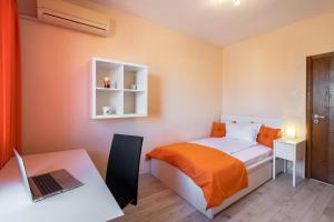 een slaapkamer met een bed en een bureau met een laptop bij BGApartments - Chataldzha in Varna