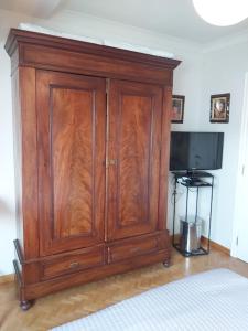 a wooden cabinet in a room with a television at B&B De Mansarde in Diest