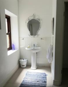 a white bathroom with a sink and a mirror at Paternoster Place in Paternoster