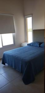 1 Schlafzimmer mit einem blauen Bett und 2 Fenstern in der Unterkunft CABAÑAS PARQUE TERMAL DOLORES in Dolores