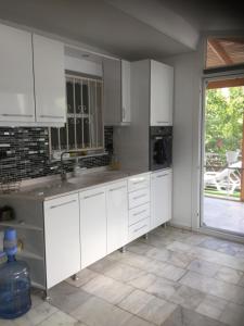 a kitchen with white cabinets and a large window at Villa Anja in Kuşadası