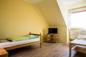 een slaapkamer met een bed en een tv in een kamer bij Logia Hotel garni in Neuharlingersiel