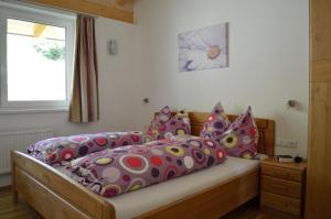 a bedroom with a bed with colorful pillows and a window at Haus Klein Rosental in Neukirchen am Großvenediger