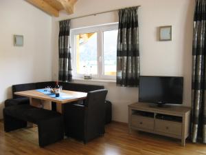 a living room with a table and a television at Haus Klein Rosental in Neukirchen am Großvenediger