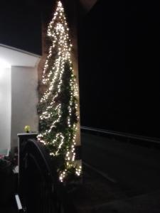 ein Weihnachtsbaum mit Lichtern in einem Zimmer in der Unterkunft Casa Via Castelmonte in Cividale del Friuli