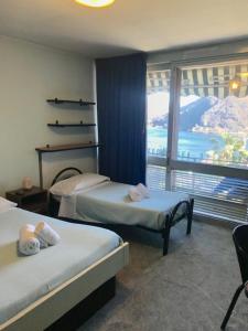 a hotel room with two beds and a large window at Hotel Carillon in Lavena Ponte Tresa