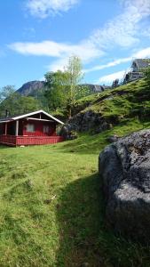 a red house in a field with a large rock at Hytte ved Preikestolen in Forsand