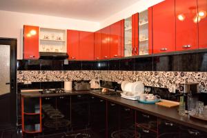 a kitchen with red cabinets and black and white tiles at Pensiunea Vraja in Giuleşti +84 photos