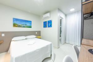 a white room with a bed and a table at Liiv Cobogó - Natal Ponta Negra in Natal