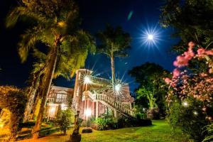a night shot of a house with palm trees and lights at Acasarosa Hostel in Praia Grande