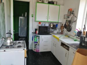 a kitchen with green cabinets and a stove top oven at Hospedaje Mancora in Santiago