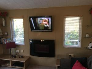 STUNNING LODGE - HOME FROM HOME Kippford, Dalbeattie في دالبيتي: غرفة معيشة مع تلفزيون بشاشة مسطحة على الحائط