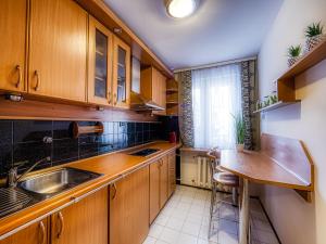 uma cozinha com armários de madeira, um lavatório e uma mesa em Apartament Krupówki Center em Zakopane