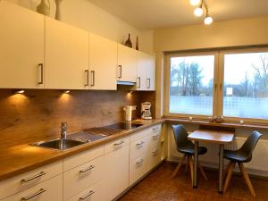 シャルボイツにあるHaus am Heidebeckの白いキャビネットとテーブル、窓付きのキッチン