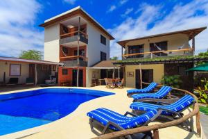 uma villa com uma piscina e cadeiras azuis em Galapagos Cottages em Puerto Ayora