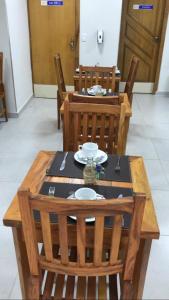 una mesa de madera y sillas con una mesa y platos. en HOTEL CASABLANCA, en Aparecida de Goiania