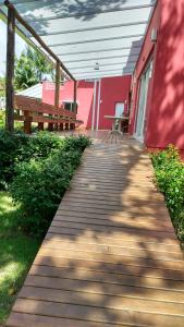 a wooden walkway leading to a red building with benches at Vila Juma in Camburi