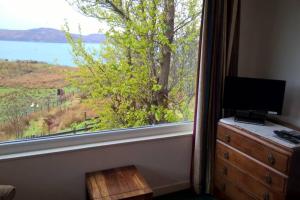 a bedroom with a window with a television and a dresser at Bothan na Tilleadh in Achiltibuie