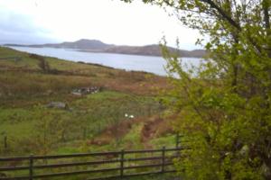 a fence on a hill next to a body of water at Bothan na Tilleadh in Achiltibuie