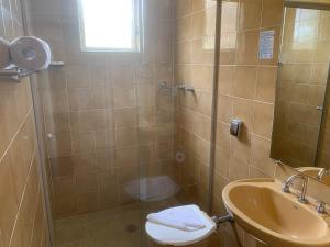 a bathroom with a shower and a toilet and a sink at Pousada Vila Floratta in Campos do Jordão