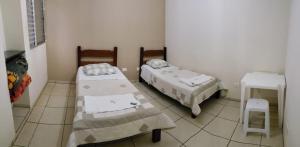 a room with two beds and a stool in it at HOTEL CENTRAL in Juruaia +4 photos