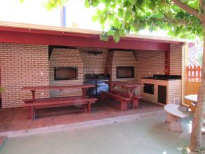 a patio with two picnic tables and a fireplace at Pousada Recanto da Barra in Florianópolis