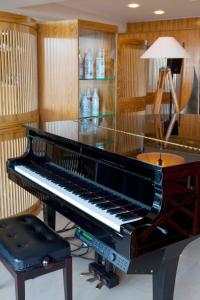 a piano in a room with a lamp and a stool at Hotel Le Grand Pavois in Fécamp
