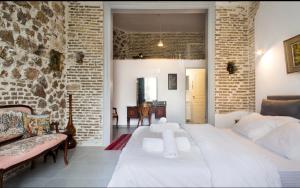 a bedroom with a white bed and a brick wall at A litte Taste of Home Guest House in Athens