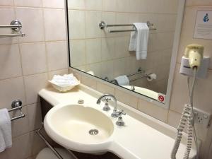 
a bathroom with a sink, mirror, and soap dispenser at Country Gardens Motor Inn in Toowoomba
