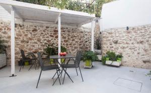 patio con mesa, sillas y pared de ladrillo en A litte Taste of Home Guest House, en Atenas