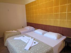 two beds in a hotel room with towels on them at Pousada Recanto da Barra in Florianópolis