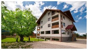 a large white building with a tree in front of it at Pensiunea Aron 2 in Bran