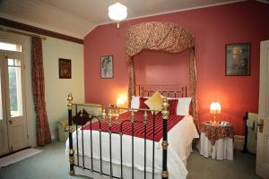 a bedroom with a canopy bed with red walls at Forgandenny House B&B in Mudgee