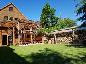 a large wooden house with a yard and a church at Penzion pod Lipou in Liptovský Ján