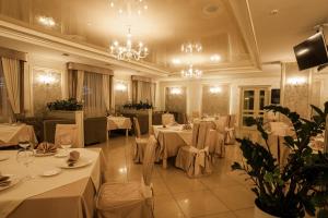 a restaurant with white tables and chairs and a chandelier at Maria Garden hotel & restaurant in Ivano-Frankivsʼk