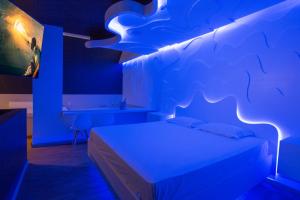 a bedroom with a bed with blue lights on it at Tout Motel (Adults Only) in Campinas