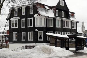 een groot zwart-wit huis met sneeuw ervoor bij Ferienwohnung Linnea - TOP Lage direkt in Braunlage in Braunlage +6 foto's