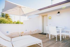 a white patio with a table and chairs and an umbrella at Una Perla Nel Verde in Putignano