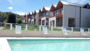 a swimming pool with chairs and a building at Posada y spa Las Golondrinas in Sierra de la Ventana