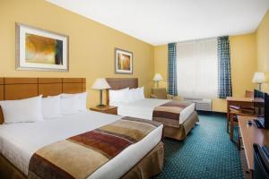 um quarto de hotel com duas camas e uma secretária em Baymont by Wyndham Helena em Helena