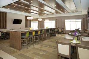 une grande salle à manger avec un long bar et des chaises dans l'établissement Wingate by Wyndham Calgary Airport, à Calgary