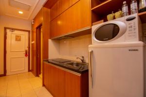 a kitchen with a sink and a microwave on top of a refrigerator at Royale Chulan Kuala Lumpur in Kuala Lumpur