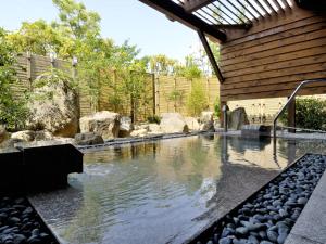 白浜町にあるオーベルジュ サウステラスの岩と家のある裏庭のスイミングプール