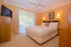 a bedroom with a large white bed and a window at Rocky Mountain Cottage in Blackheath