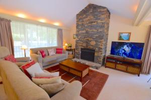 a living room with a stone fireplace and a couch at Rocky Mountain Cottage in Blackheath